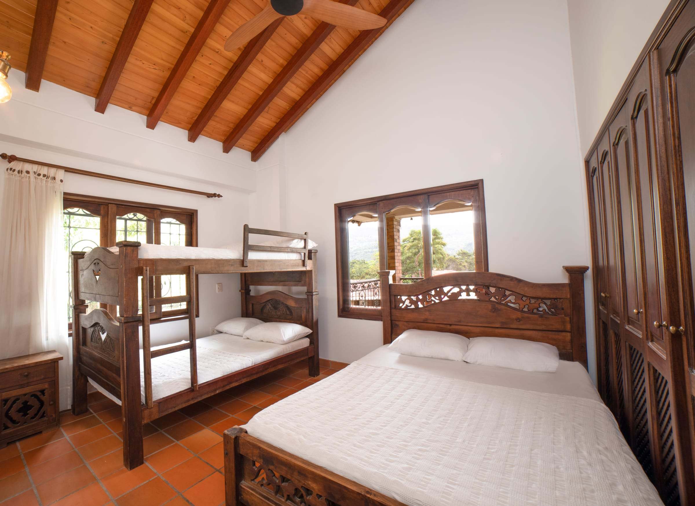 Habitación con techo de madera, cama queen y camarote
